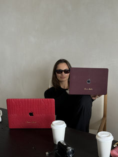 a woman sitting at a table with two laptops