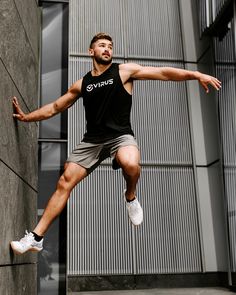 a man in black shirt and grey shorts doing a trick on a wall with his hands out