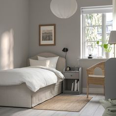 a white bed sitting next to a window in a bedroom