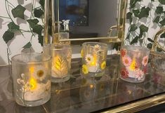 four glass vases sitting on top of a table next to a mirror and plant