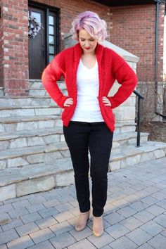 a woman standing in front of some steps wearing black pants and a red cardigan