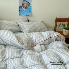 an unmade bed in a room with a painting on the wall and pictures above it