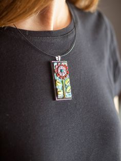 a woman wearing a black shirt and a necklace with flowers on it's back