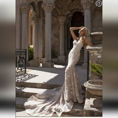 a woman in a wedding dress standing on some steps with her arms behind her head