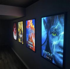 a row of movie posters on the wall in a dark room with wood flooring