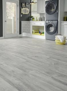 a laundry room with grey floors and white cabinets is shown in this image, there are two washers next to the dryer