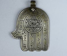 a metal hamsa with an intricate design on it's front and back sides