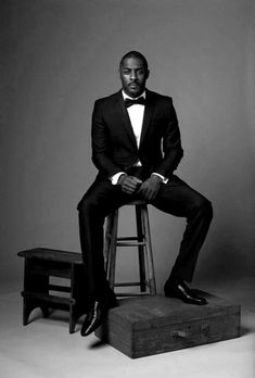 a man in a tuxedo sitting on a stool