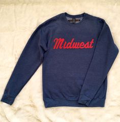 You're Midwestern and you're so darn proud, you want to wear a sweatshirt about it! This print is flocked (think fuzzy, velvety, rubbing-your-shirt-a-little-too much soft) in bright red script. The sweatshirt color is called heather denim. Unisex/Men's sizing Fabric 7.5 oz. fleece 80% ring-spun cotton/20% polyester Reactive-dyed for longer-lasting color Side-seamed, drop shoulders with crew neck Ribbed cuffs, neckline, and waistband with 5% Spandex Tear Anywhere label Flocking, Bright Red, Minneapolis, Graphic Sweatshirt, Crew Neck, Sweatshirts, Fabric, How To Wear, Color