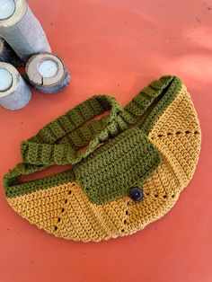 a crocheted purse sitting on top of a table next to two candles and some other items