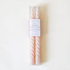 two pink candles sitting in a package on a white surface with the label twisted candles