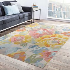 a living room with a gray couch and colorful rugs on the wooden flooring