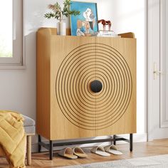 a wooden cabinet with an abstract design on the front and bottom, sitting in a living room