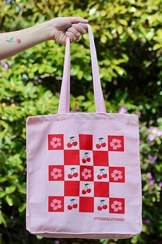 Pack up a picnic in this vibrant pink tote bag, displaying a checkerboard of cherries and cherry blossoms. **Care/Import** * Made of durable 15 oz pink cotton canvas. * Machine wash in cold, tumble dry on low, iron on low * Made in the USA **Dimensions** * 10" W x 14" H x 5" G | Overseasoned Cherry Picnic Tote Bag at Free People in Pink Summer Cotton Bag For Picnic, Cotton Summer Picnic Bag, Cotton Picnic Bag For Summer, Red Spring Picnic Bag, Spring Picnic Cotton Bag, Pink Square Bag For Spring, Retro Pink Bags For Spring, Retro Pink Bags For Summer, Retro Pink Summer Bags