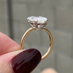 a close up of a person's hand holding a ring with a diamond on it