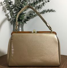 "1950s 1960s Vinyl Top Handle Handbag, Vintage Purse, Mid Century Accessory  Classic 50s 60s top handle pocketbook with Lucite trim that runs across the top of the bag. Gold tone metal hardware with a pretty thumb lift closure that works well and closes tightly. It has a single handle strap. Opens to a vinyl lining and has one interior side metal zippered pocket. There are protective feet on the bottom. Beautiful vintage condition *there are no cracks on the exterior.  There are however some min Luxury Mid-century Top Handle Bag, Classic Gold Evening Bag With Top Handle, Classic Gold Top Handle Evening Bag, Mid-century Gold Evening Bag, Classic Rectangular Evening Bag For Vintage Events, Gold Retro Bags, Gold Retro Bags With Gold-tone Hardware, Vintage Rectangular Evening Bag For Luncheon, Retro Gold Bags With Gold-tone Hardware