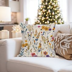 a living room with a christmas tree in the background and pillows on the couches