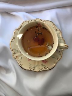 a tea cup filled with liquid sitting on top of a white cloth covered tablecloth