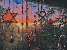 the sun is setting behind many hanging stars and lanterns, with trees in the background