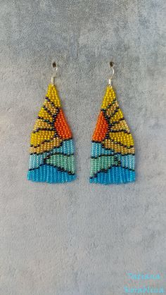 two pairs of beaded triangle earrings on a gray surface with blue, yellow and red beads