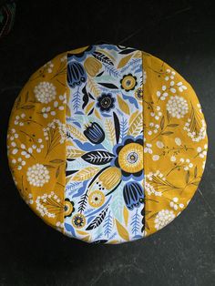 a yellow and blue flowered plate on a black surface