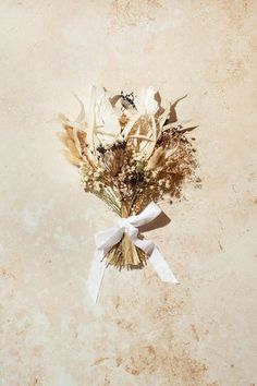 a bouquet of dried flowers tied to a white ribbon on a beige background with copy - space