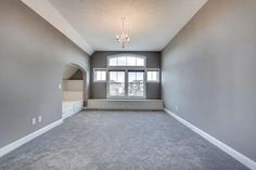 an empty living room with gray walls and carpet