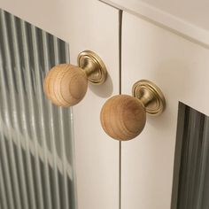 two wooden knobs on the front of a white cabinet