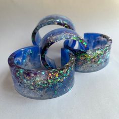 three blue bracelets sitting on top of a white table covered in holographic paint