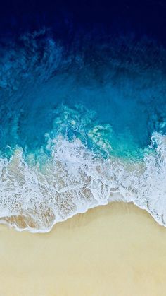 an aerial view of the ocean and beach with waves coming in from the shore,