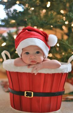 a baby wearing a santa hat sitting in a cupcake