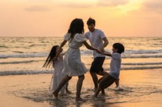 a family playing on the beach at sunset