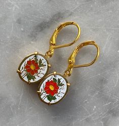 Floral Vintage Enamel Earrings. 10x12 mm oval fun vintage Japanese enamel floral charm earrings with Coral Orange flowers on a white background set in gold. New US made lead and nickel free open back prong settings. Nickel free plated brass shell lever back ear wires. Comes boxed and ready for gift giving! Custom orders are always welcome! Gold Oval Enamel Jewelry, Oval Gold Enamel Jewelry, Vintage Enamel Flower Earrings, Vintage Gold Flower Earrings With Enamel, Vintage Gold Teardrop Flower Earrings, Gold Vintage Teardrop Flower Earrings, Vintage Yellow Gold Flower Earrings For Gift, Nickel-free Gold Oval Earrings, Oval Jewelry With French Hook For Gifts