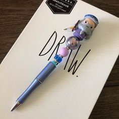 a pen sitting on top of a piece of paper next to a small toy figure