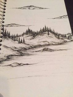 a pencil drawing of mountains and trees in the distance on a notepad with a pen