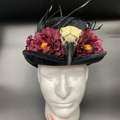 Black velvet top hat decorated with plastic crow skull, feathers, and flowers. One size. Steampunk Costume Hats For Halloween Masquerade, Gothic Costume Hats And Headpieces For Carnival, High Crown Costume Accessories For Halloween Party, High Crown Halloween Costume Accessories For Costume Party, Steampunk Headpiece For Halloween Costume, Steampunk Headpieces For Halloween Masquerade, Steampunk Headpieces For Masquerade Halloween, Steampunk Halloween Festival Headpiece, Gothic High Crown Costume Accessories For Costume Party