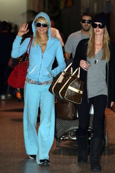 two women in matching outfits walking through an airport