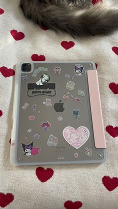 a cat laying on top of a bed next to an ipad case with stickers