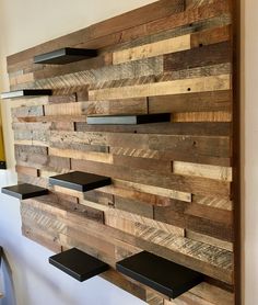 a wooden wall mounted to the side of a white wall with shelves on each side