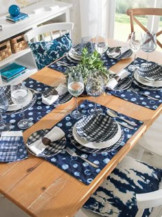 the table is set with blue and white place mats, silverware, and napkins