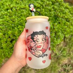 a hand holding a glass with a cartoon character on it