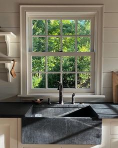 a kitchen sink sitting under a window next to a counter