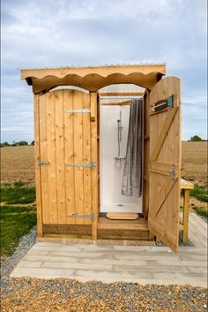 an outdoor shower in the middle of a field with doors open to reveal it's outside