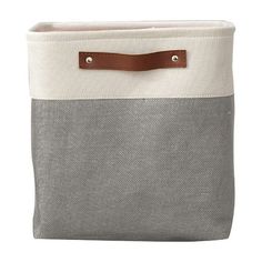 a gray and white tote bag with brown leather handles on the front, sitting against a white background