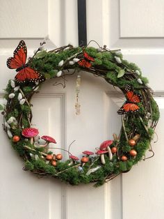 a green wreath with orange butterflies hanging from the front door and moss growing on it