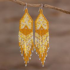 yellow and white beaded earrings hanging from a tree branch