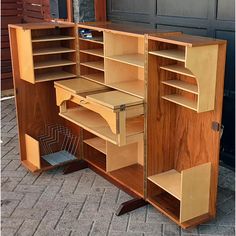 a wooden desk with drawers and shelves on the side of it, sitting in front of a garage door