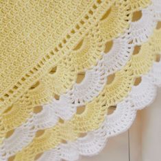 a yellow and white crocheted blanket sitting on top of a table