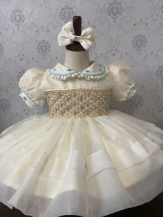 These are pre-order dresses. All of them are handmade smocking and they take from 6-8 weeks to ship. Thank you for your patience and supporting a small business. Clothing Care Instructions Most items can be washed safely in cold water on delicate cycle and hung to dry. If the item that you are ordering has red or another bright color in it next to a white or other light color fabric please use a Shout color catcher for the first few washes to avoid bleeding. The reds are pre-washed but they are Cream Dress With Smocked Bodice For Wedding, Cream Wedding Dress With Smocked Bodice, Elegant Smocked Dresses For Baptism, Elegant Smock Dresses For Baptism, Fitted Cream Smocked Dress, Fitted Wedding Dress With Smocked Cuffs, Fitted Dress With Smocked Bodice For Baptism, Fitted Cream Smocked Dress With Smocked Cuffs, Fitted Smock Wedding Dress