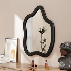 a mirror sitting on top of a wooden table next to a vase and other items